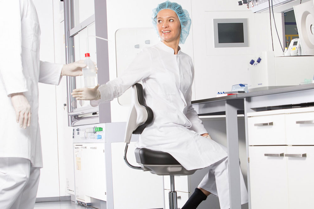 Frau sitzt auf bimos Laborstuhl in einem Labor